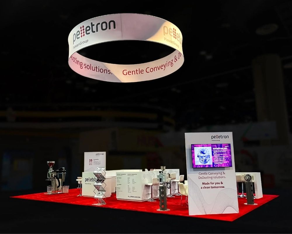 Pellettron custom trade show booth with industrial equipment and overhead signage by Local Exhibits