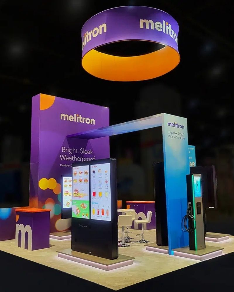 Melitron digital display solutions trade show booth with interactive screens and overhead signage by Local Exhibits