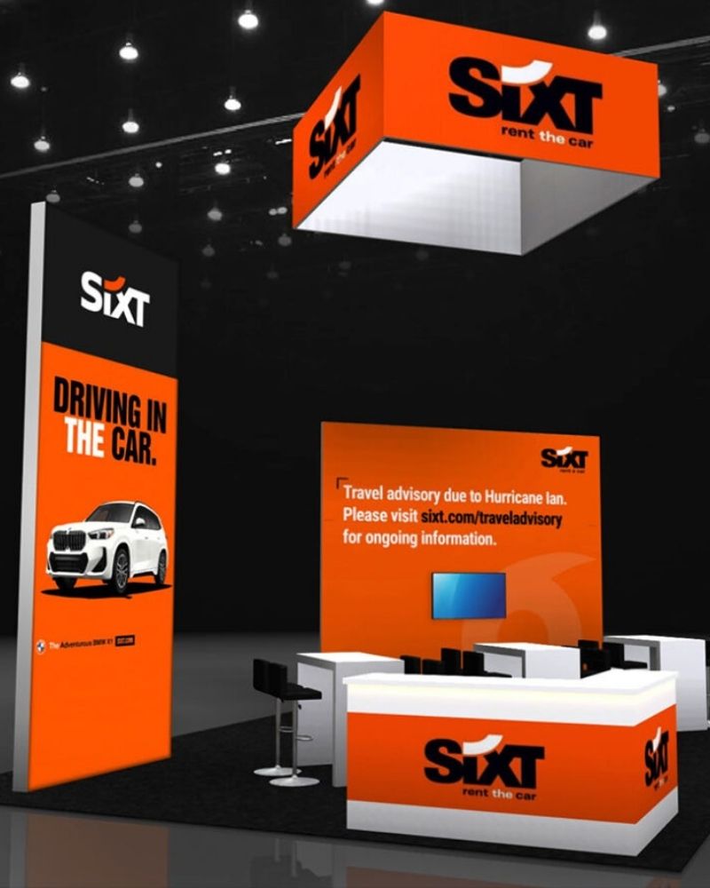SIXT branded trade show booth with overhead signage and product display by Local Exhibits