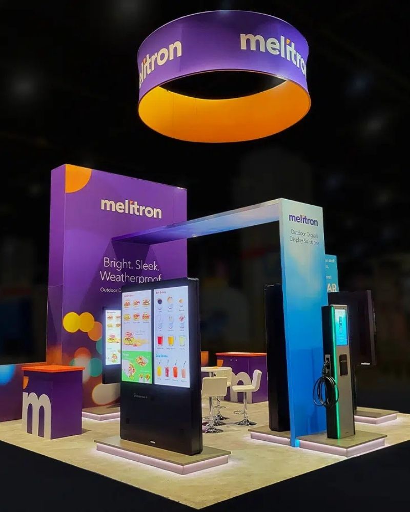 Melitron trade show booth with digital display kiosks and overhead signage by Local Exhibits
