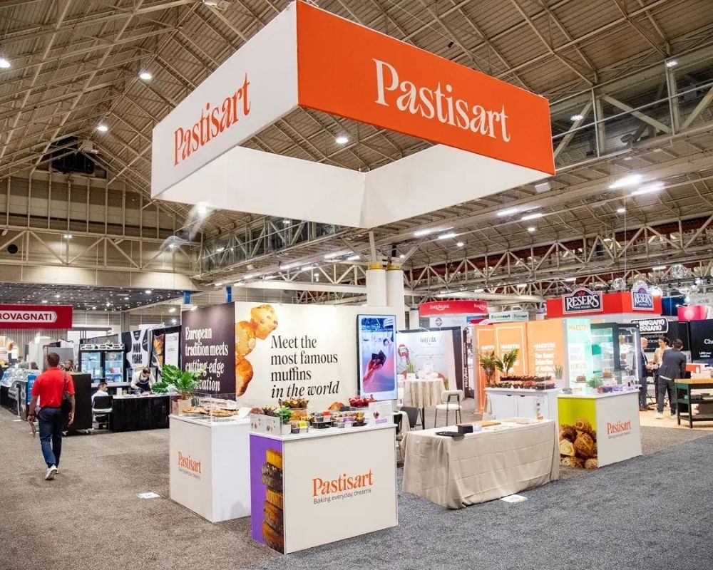 Custom trade show booth design with overhead signage and product display by Local Exhibits