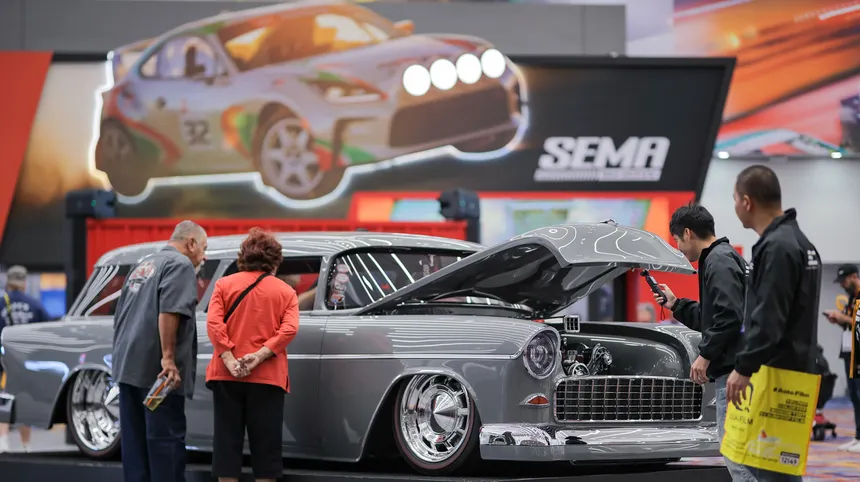 SEMA Show custom classic car display with open hood, automotive signage, and attendees viewing the exhibit