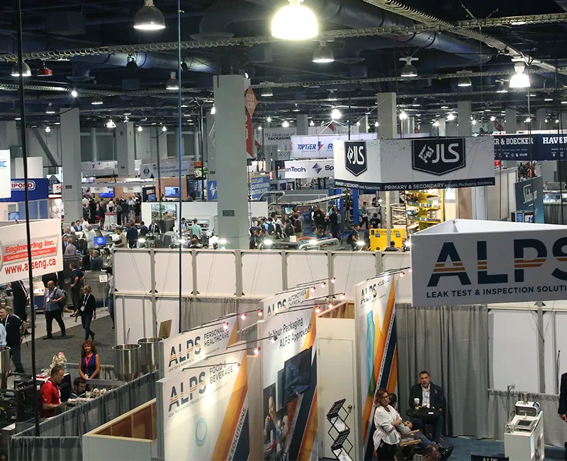 PACK EXPO exhibit floor with ALPS leak test booth, packaging solution displays, and attendees walking through the trade show